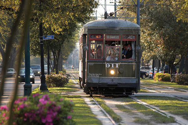 NOLA-Streetcar A NOLA Streetcar rolls down a lush street.